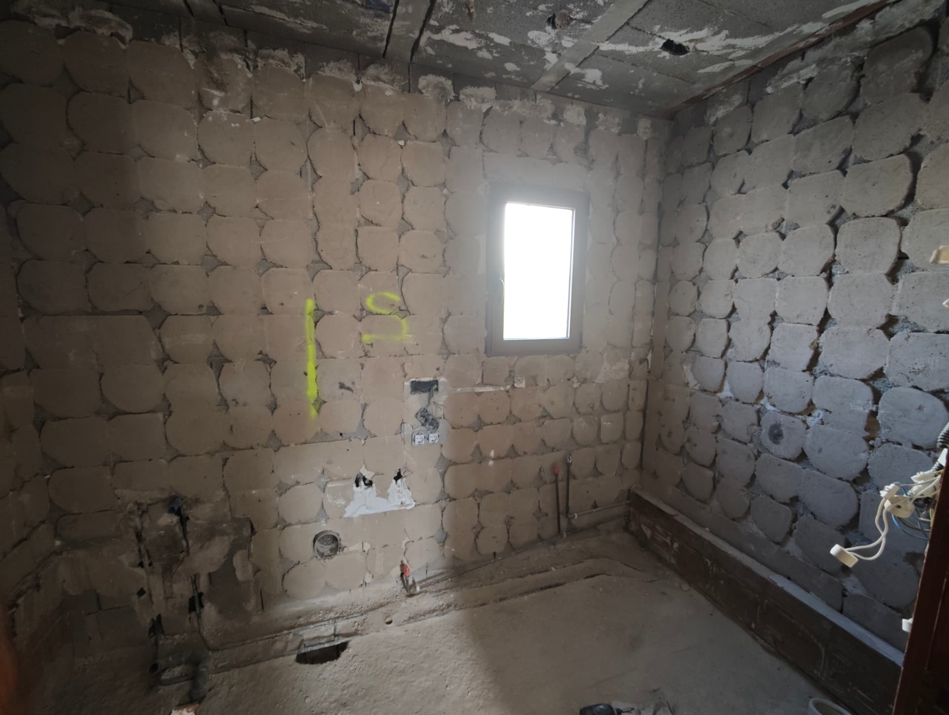 Baño de la planta superior en bruto antes de la reforma: paredes de bloque, instalaciones vistas y sin acabados
