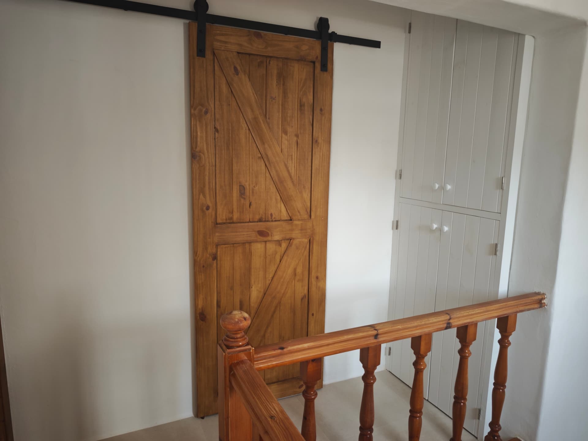 Distribuidor superior terminado con puerta corredera de madera, armario empotrado lacado y paredes lisas