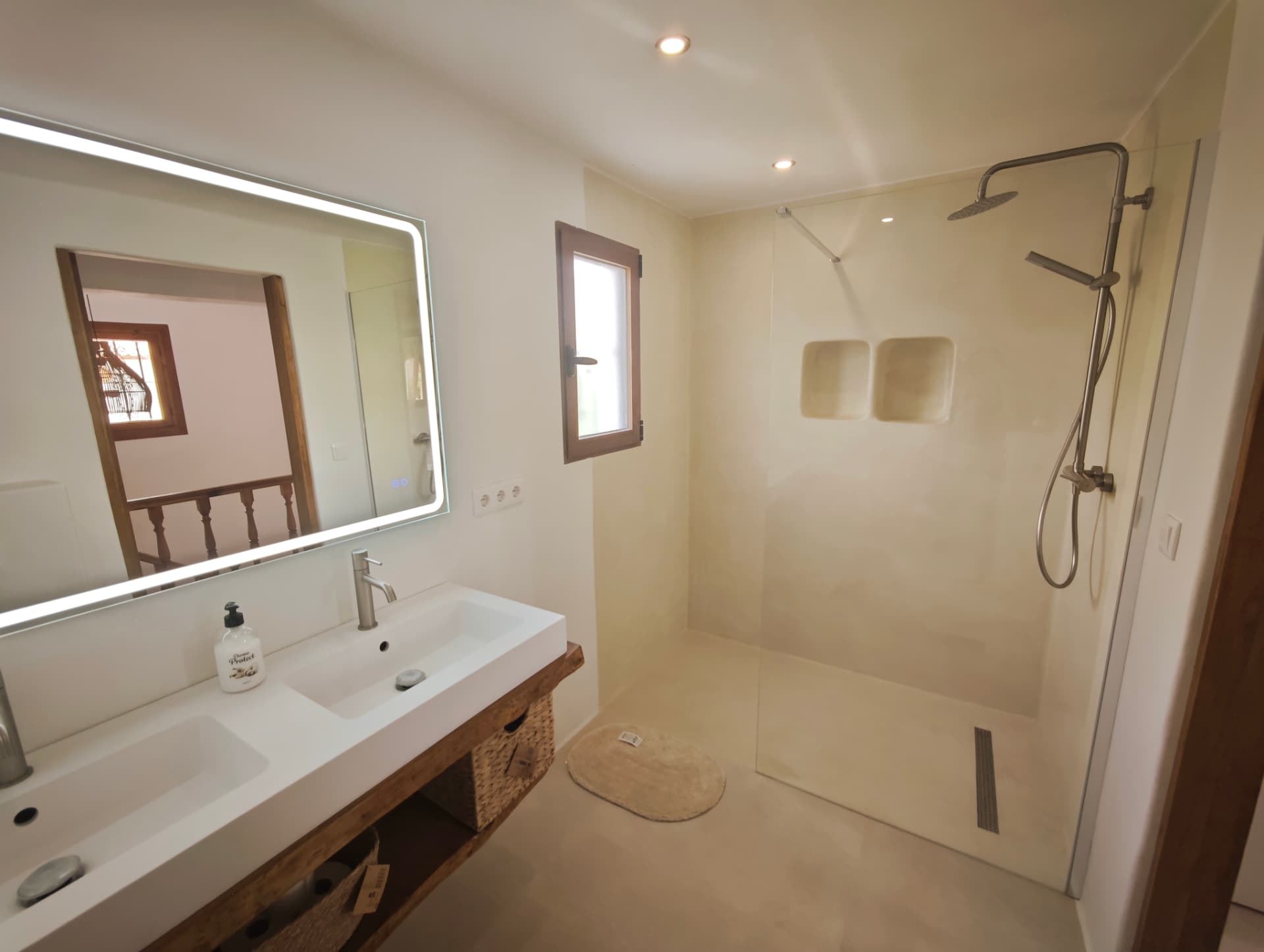Baño reformado con microcemento continuo, ducha de obra con hornacinas y encimera de madera maciza