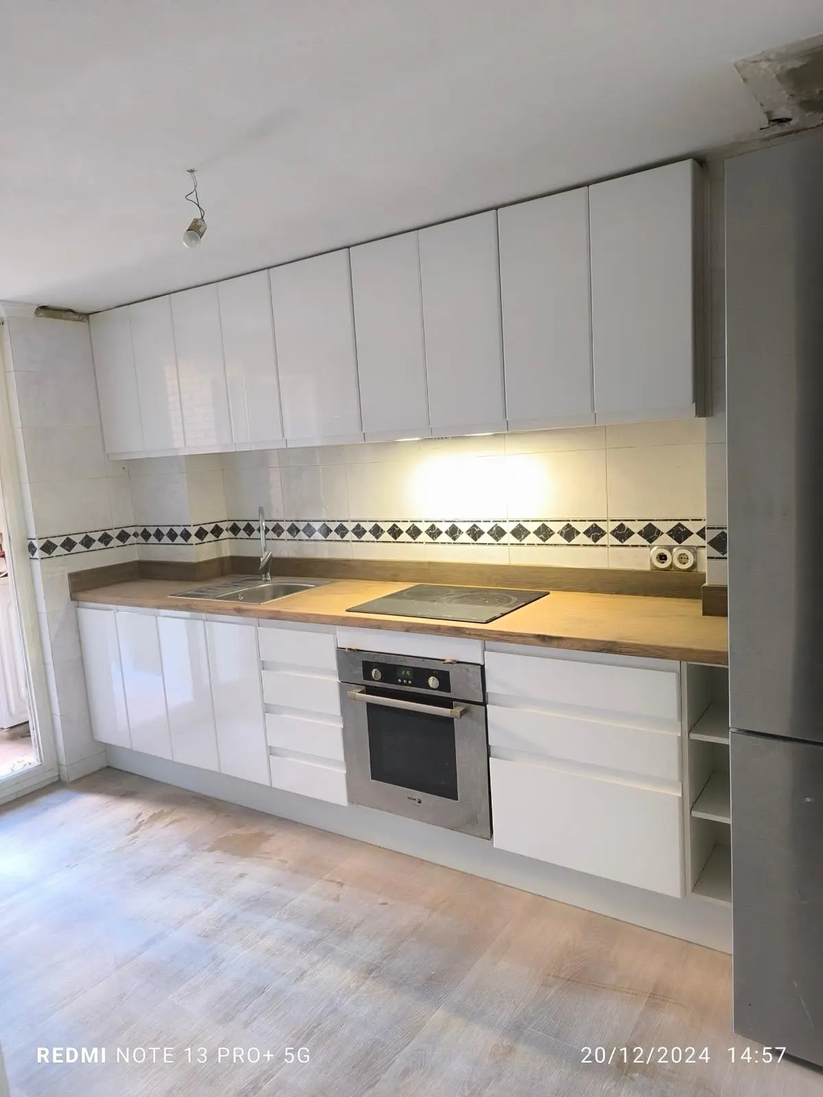 Cocina blanca con muebles altos hasta el techo y encimera de madera